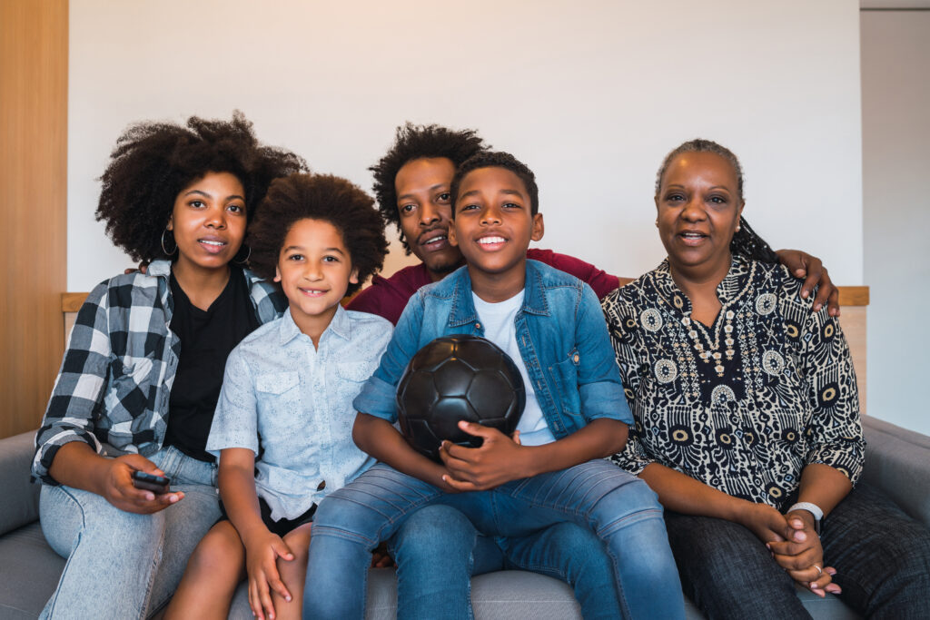 5 Motivos Para Você Contratar um Plano de Saúde: A Importância De ter Um Plano De saúde. 1 familia de varias geracoes assistindo partida de futebol em casa 1